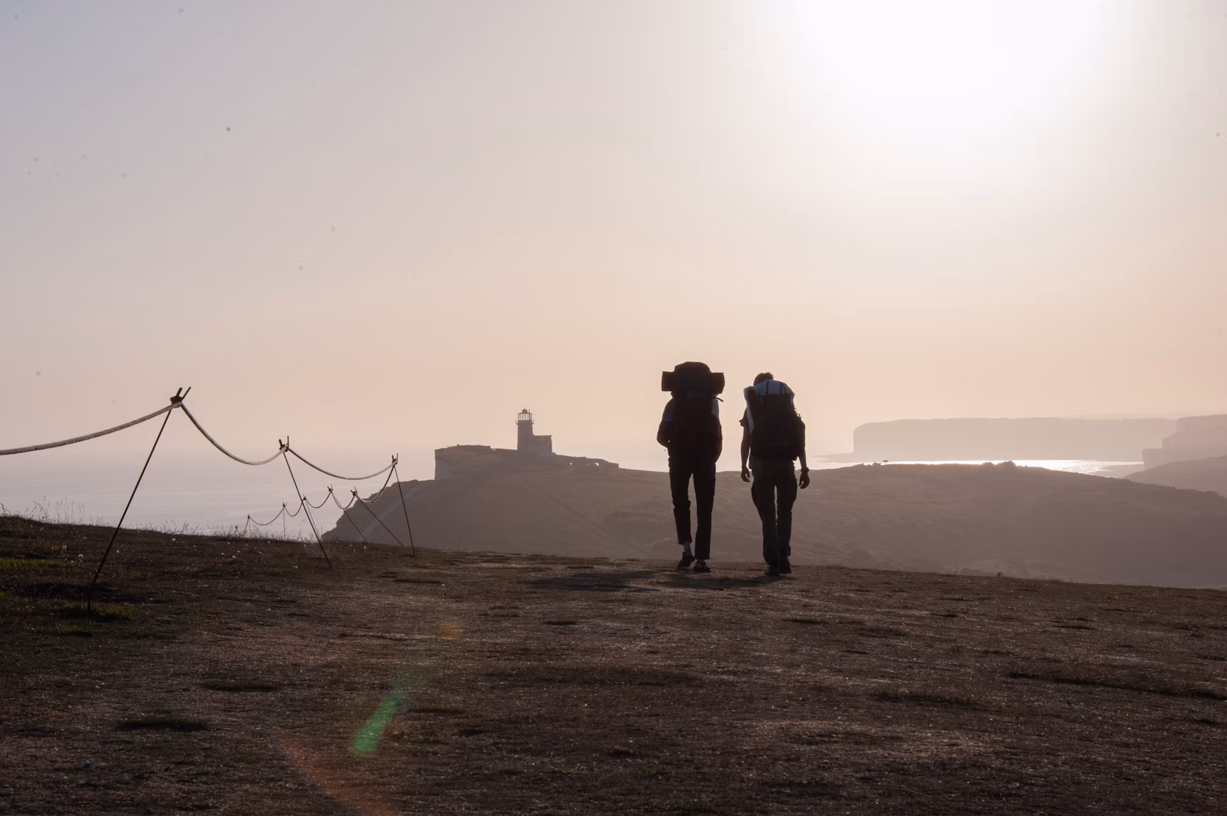 Two backpackers approaching a misty coastal view