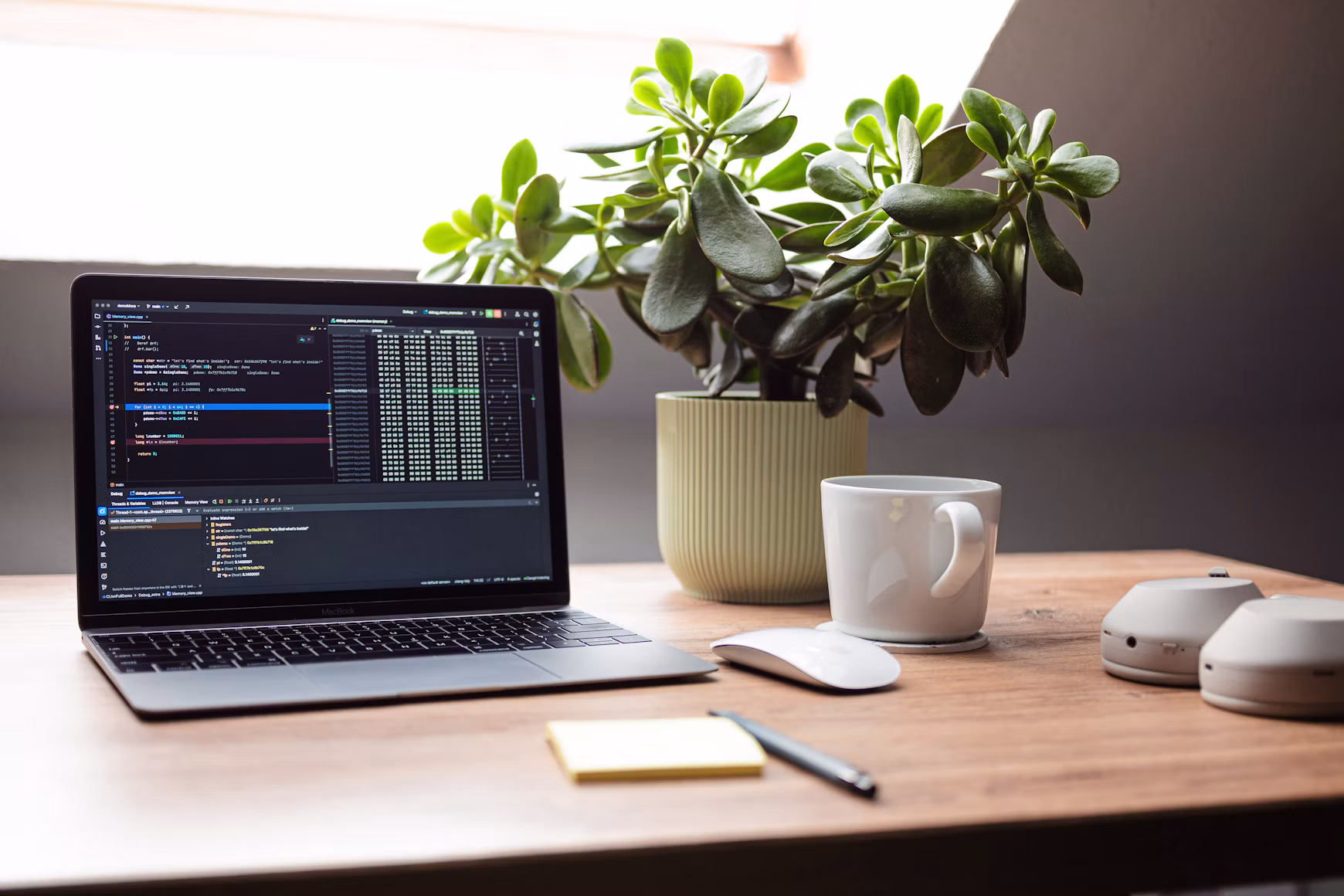 Laptop showing code beside a plant and coffee mug