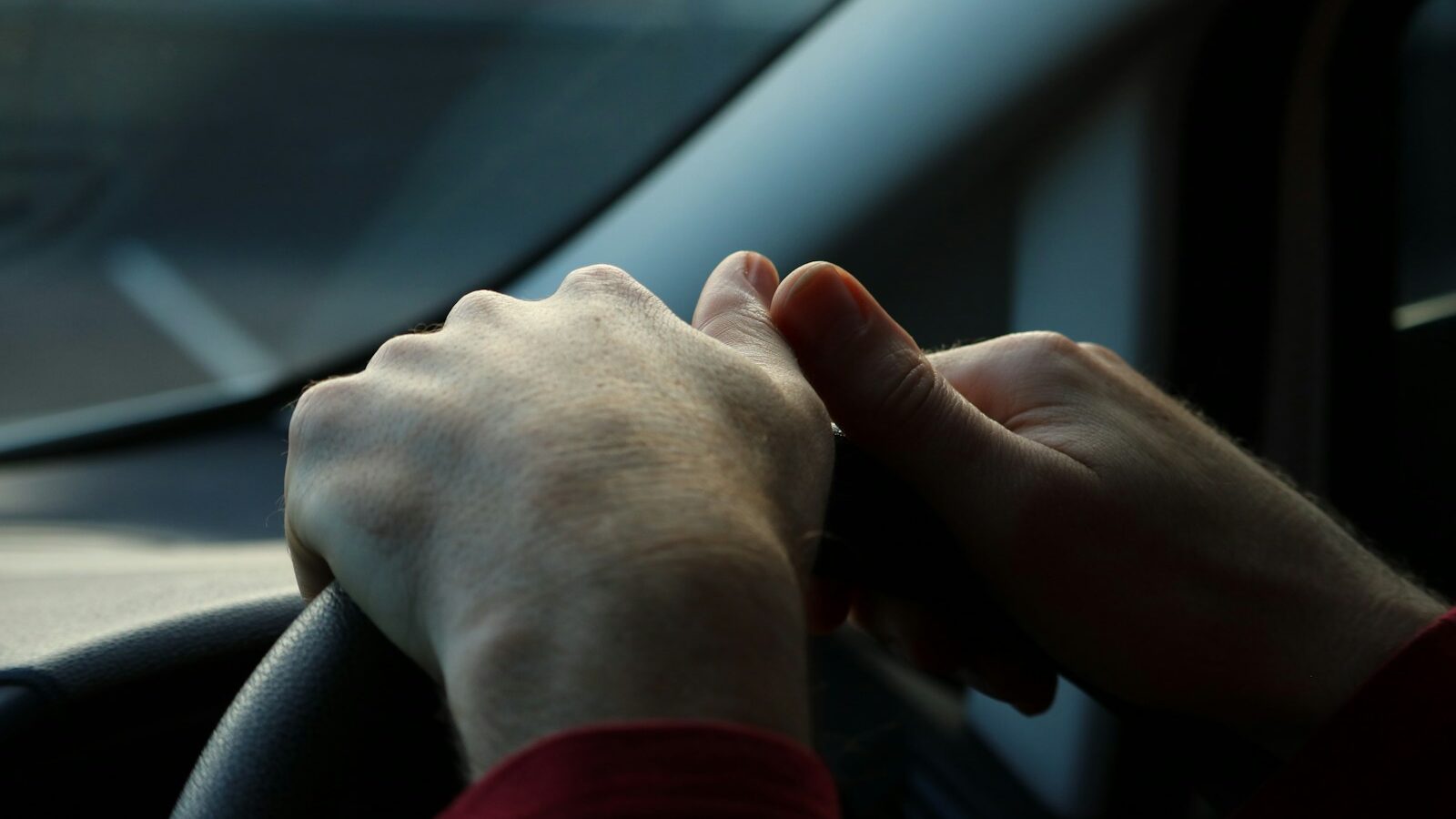 Hands holding a steering wheel while driving