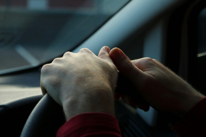 Hands holding a steering wheel while driving